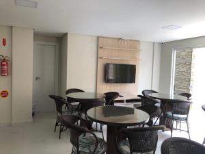 Habitación con mesas, sillas y TV de pantalla plana. en RESIDENCIAL FAGUNDES II, en Florianópolis