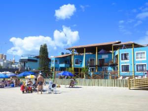 a group of people on a beach with blue buildings at Residencial Vila do Sol, Apartamentos com pé na areia in Bombinhas