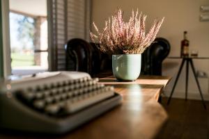 eine Computertastatur und eine Vase Blumen auf dem Tisch in der Unterkunft Creative Design House Golf & SPA in Pozzolengo