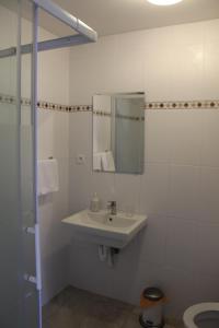 La salle de bains blanche est pourvue d'un lavabo et d'un miroir. dans l'établissement Logie Rotem, à Dilsen-Stokkem