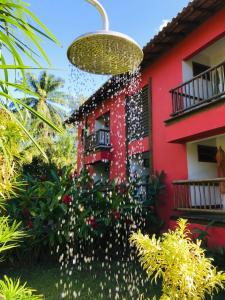 uma casa vermelha com uma planta florida à sua frente em Arpoador Flat em Itacaré