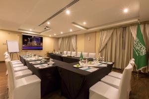 une salle de conférence avec de longues tables et des chaises blanches dans l'établissement Holiday Jazan Hotel, à Jazan