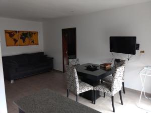 sala de estar con mesa, sillas y TV en DEPARTAMENTOS SERENA II en Mar del Plata