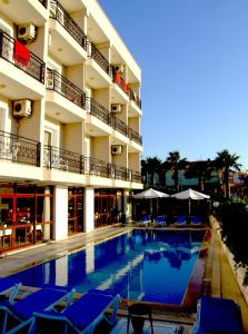 a hotel swimming pool with blue chairs and umbrellas at Albayrak Hotel in Cesme