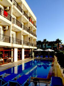 a hotel swimming pool with blue chairs and umbrellas at Albayrak Hotel in Çeşme