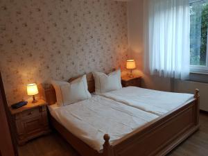 a bedroom with a large bed with two lamps on tables at Ferienhaus "Am Gehre" in Bad Berleburg
