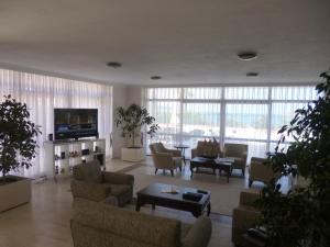 a living room with couches and chairs and a television at Albayrak Hotel in Çeşme