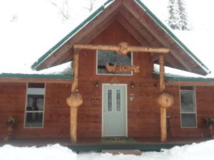 a log cabin in the snow with a door at Alaska's Northland Inn in Trapper Creek