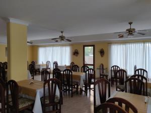 a dining room with tables and chairs and windows at Hotel Castilla in Villa Gesell