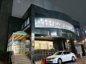 um carro branco estacionado em frente a um edifício em Gallery Hotel BnB em Jeju