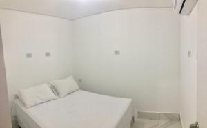 a small white room with a bed in it at Apartamento no Edifício Florida Terrace in Matinhos