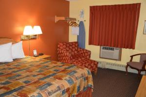 a hotel room with a bed and a chair at Burnsville Inn & Suites in Burnsville