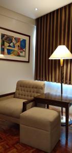 a living room with a couch and a table and a lamp at Tropicana Suites in Manila