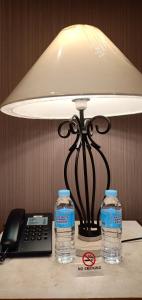 a lamp on a table with two bottles of water at Tropicana Suites in Manila