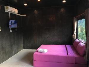 a pink bed in a room with a tv at Bann Ton Kho in Khao Kho
