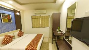 1 dormitorio con cama, mesa y TV en Hotel Jyoti, en Rajkot