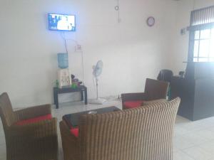 a living room with chairs and a tv on the wall at skyz hostel in Padang