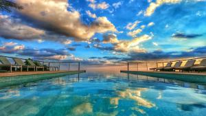 a swimming pool with a cloudy sky in the background at The View in Al Ḩamrāʼ