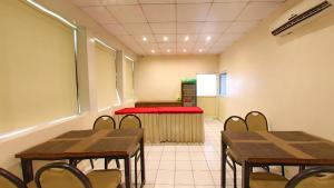 una sala de espera con mesas y sillas y un banco rojo en Hotel Jyoti, en Rajkot