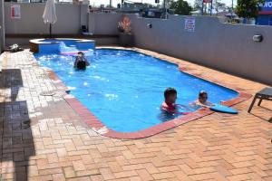 2 persone nuotano in una piscina di Best Western Bundaberg City Motor Inn a Bundaberg