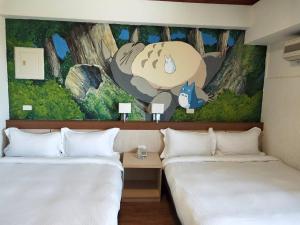 2 Betten in einem Hotelzimmer mit Wandbild in der Unterkunft Little Paradise Inn in Altstadt von Hengchun