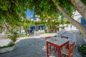 una mesa y sillas bajo un árbol frente a un edificio en Despina Hotel, en Agia Anna de Naxos