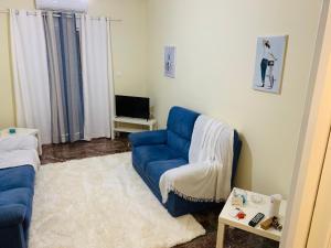 uma sala de estar com um sofá azul e uma televisão em Small Apartment in Markopoulo center em Markopoulo Mesogaias
