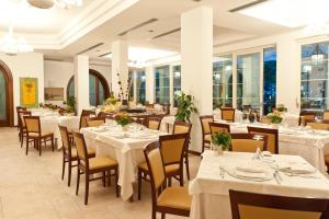 a restaurant with white tables and chairs and windows at Hotel Belvedere in Milano Marittima
