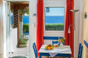 a dining room with red curtains and a table with fruit at Mirtopolis in Myrtos