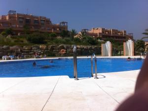 a swimming pool with people swimming in the water at Penthouse, Casares del Sol, Malaga in Casares