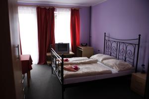 a bedroom with a bed with pink walls and windows at Pension Zlata Noha in Bratislava