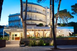 a large white building with trees in front of it at Hotel Belvedere in Milano Marittima