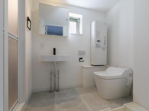 La salle de bains blanche est pourvue de toilettes et d'un lavabo. dans l'établissement AOCA KAMINOGE 302, à Tokyo