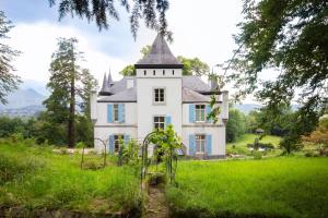 una vieja casa blanca con una torre en un campo verde en Château de Druon, en Sévignacq-Meyracq