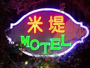 a neon sign that says mote on a wooden wall at Midi Motel Pingtung Branch in Pingtung City