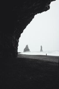 a black and white photo of a beach with two large rocks at Hótel Kría in Vík