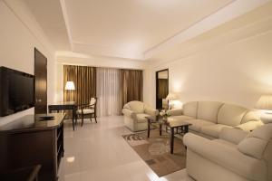 a living room with a couch and a tv and a room at Mercure Chiang Mai in Chiang Mai