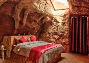 - une chambre avec un lit dans une grotte en pierre dans l'établissement Captains Desert Camp, à Wadi Rum