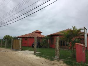 a red house on the side of a dirt road at Villa Suzana in Praia do Rosa