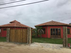 a red house with a wooden gate in front at Villa Suzana in Praia do Rosa