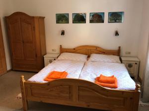 ノイシュティフト・イム・シュトゥーバイタールにあるAppartement Stubaitalのベッドルーム1室(木製ベッド1台、オレンジ色の枕2つ付)