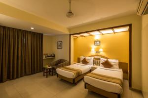 a hotel room with two beds and a chair at Hotel Park Central Koregaon Park in Pune +39 photos