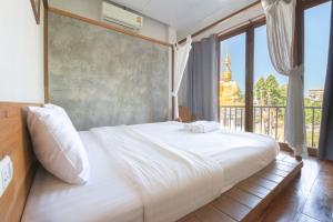 a bedroom with a large white bed with a large window at Sri Chiang Yeun House in Chiang Mai