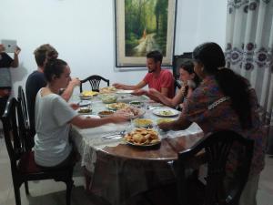 a group of people sitting around a table eating food at Helena Hostel in Dickwella +24 photos