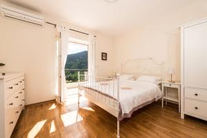 a white bedroom with a bed and a window at Lavender house with shared pool in Herceg-Novi