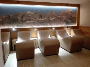 a waiting room with white chairs and a rock wall at Hotel Denny in Pinzolo