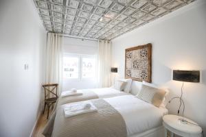 Central Lisbon Luxury Apartment في لشبونة: غرفة نوم بسرير ابيض وسقف متهالك