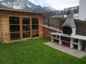 un patio trasero con un horno de pizza junto a una casa en Mountainlodge Luxalpine, en San Vigilio Di Marebbe