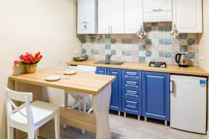 リヴィウにあるKulisha Cosy Apartmentのキッチン(青いキャビネット、木製テーブル付)