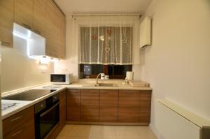 cocina con armarios de madera, fregadero y ventana en Młociny Metro Apartment en Varsovia